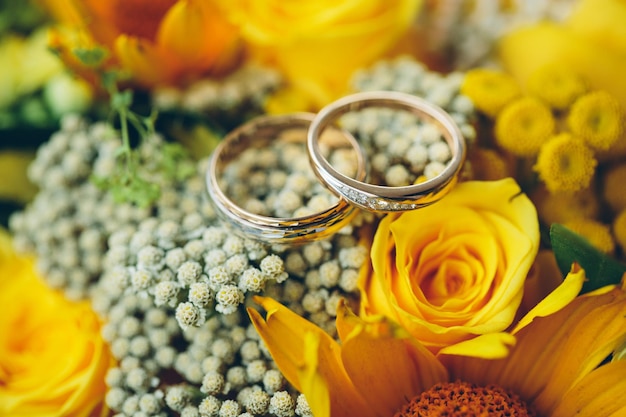 Goldhochzeitsringe auf dem gelben Brautblumenstrauß