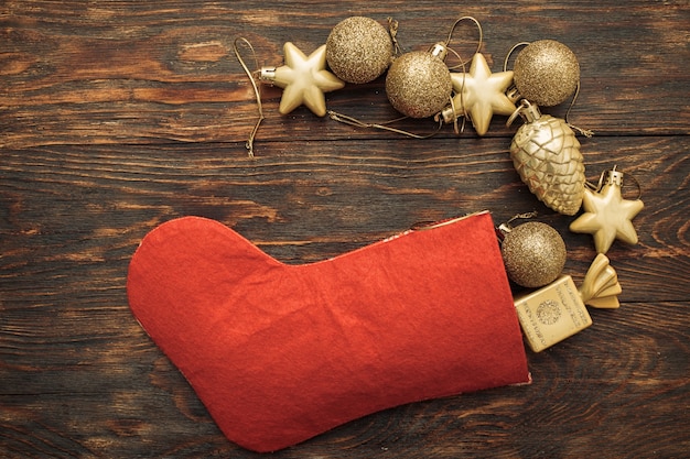 Goldkugeln und Spielzeug mit Weihnachtssocke auf Holzuntergrund