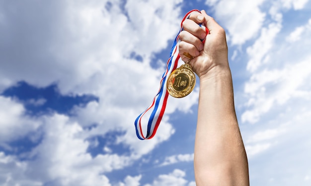 Goldmedaille mit Band in der Hand auf Hintergrund