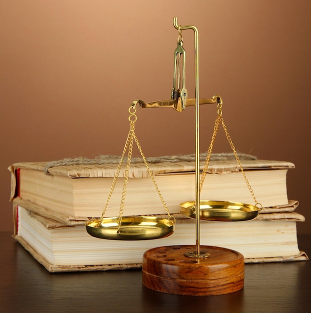 Goldwaage der Gerechtigkeit und Bücher auf braunem Hintergrund