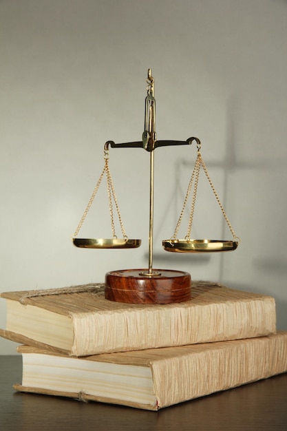 Goldwaage der Gerechtigkeit und Bücher auf grauem Hintergrund