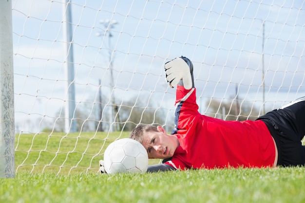 Goleiro em vermelho fazendo uma salvação