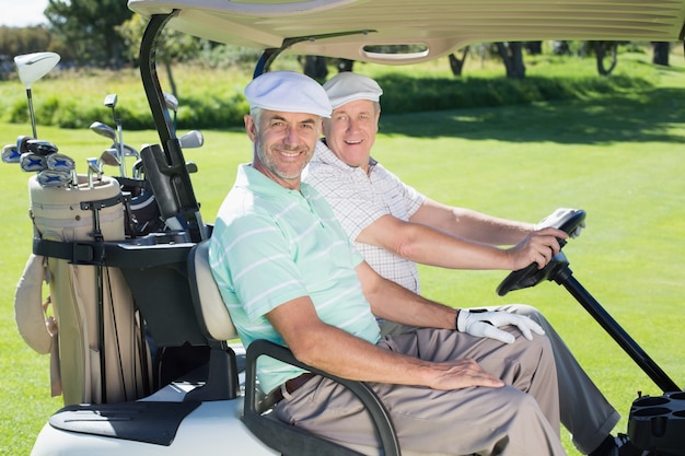 Golf amigos sonriendo a la cámara en su carrito de golf