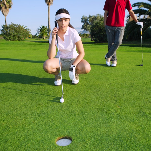 Golf mujer joven mirando y apuntando el agujero