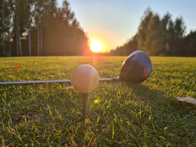 Golfball am Abschlag mit einem Fahrer auf dem Golfplatz im Hintergrund der Sonne