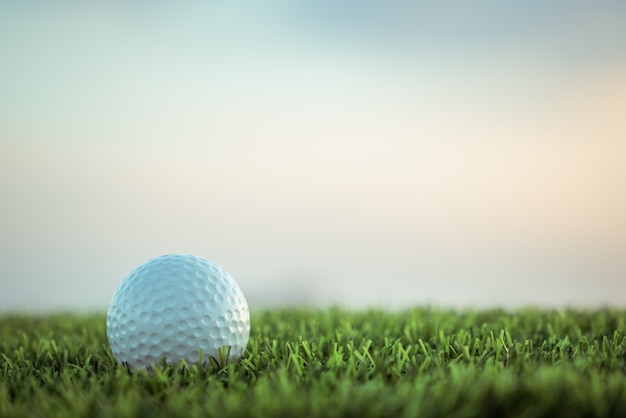 Golfball auf Gras auf Himmelhintergrund