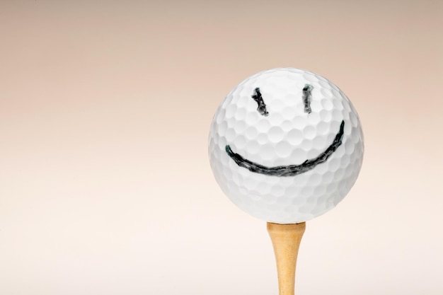 Golfball mit einem Smiley auf einem T-Stück