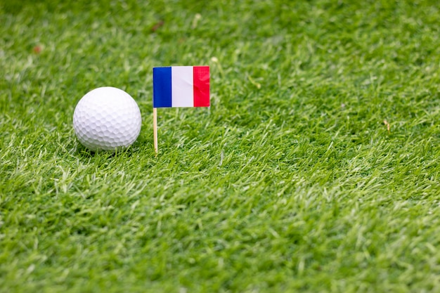 Foto golfball mit flagge von frankreich sind auf grünem gras.