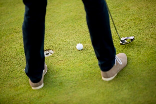 Golfball, Putter und Jungen Beine auf grün