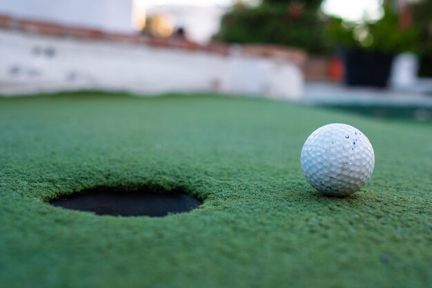 Golfball und Loch in einem Minigolffeld