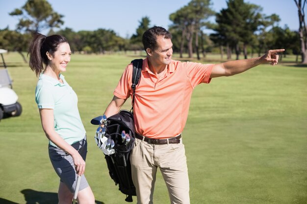 Golfer zeigt im Stehen neben der Frau
