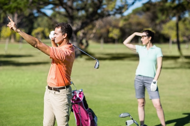 Golfer zeigt im Stehen neben der Frau