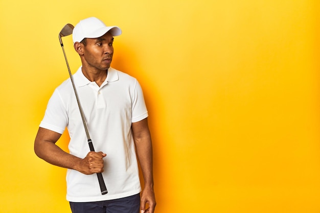 Foto golfista afro-americano em ação posando em um estúdio de fundo amarelo