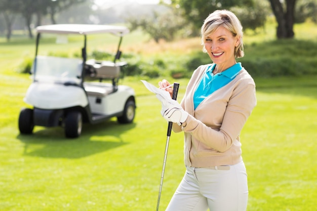 Golfista alegre de pie en el putting green