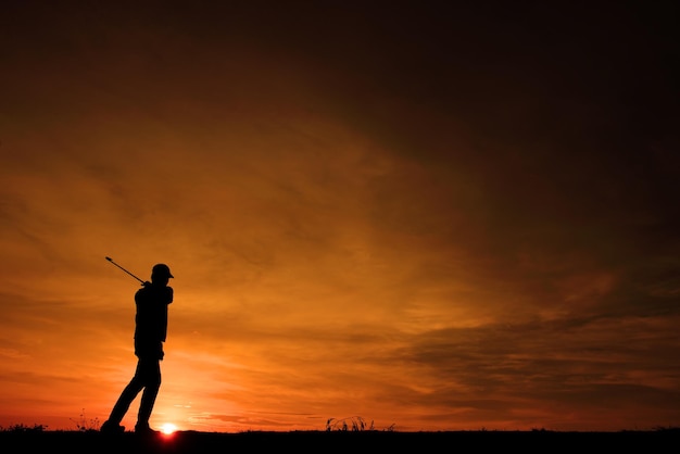 Golfista asiático de silhueta jogando golfe durante o belo pôr do sol