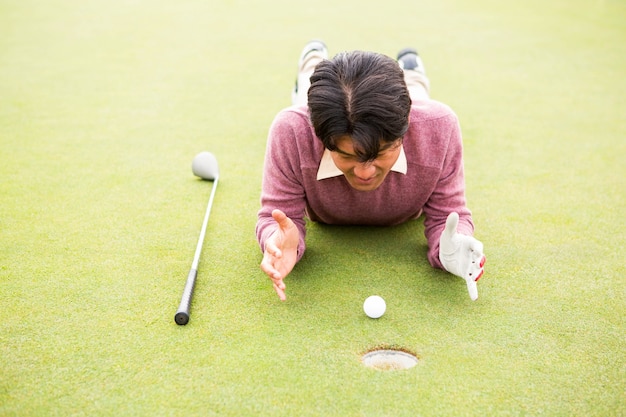 Golfista deitado perto da bola de golfe