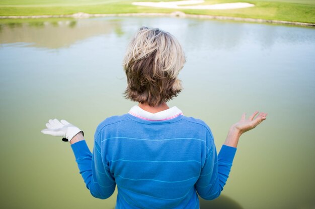 Golfista femenino confundido que mira el lago