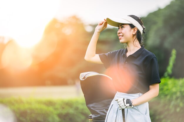 Golfista femenino profesional que detiene al club de golf en campo y que mira lejos.