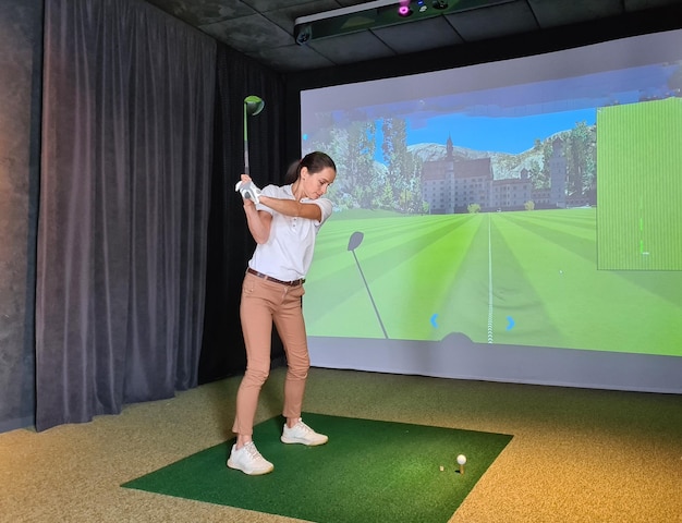 Golfista feminina joga golfe no simulador de golfe