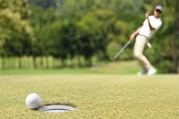 Golfista hombre animando después de una pelota de golf en un green de golf