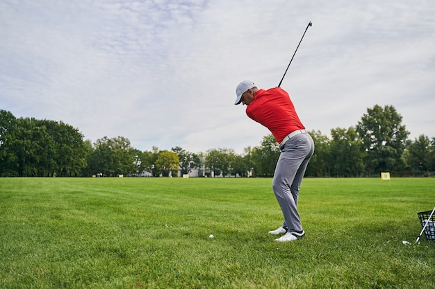 Golfista masculino serio concentrado golpeando la pelota con un palo de golf