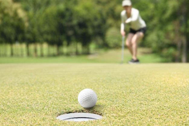 Golfista mujer animando después de una pelota de golf en un green de golf