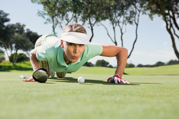 Golfista mujer soplando su bola en putting green