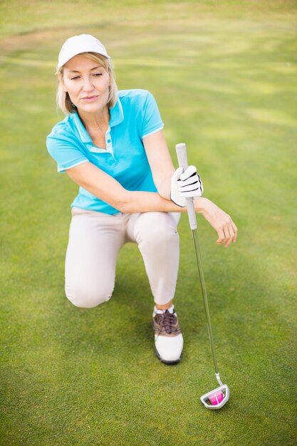 Golfista mulher agachada no campo de golfe