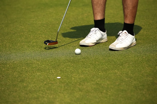 Golfista poniendo una pelota de golf en el campo de golf verde