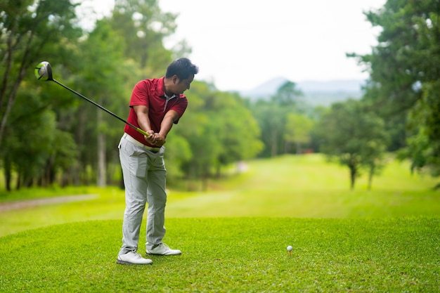 golfista que golpea la pelota de golf al agujero en el espacio abierto hermoso en campo de golf en puesta del sol.