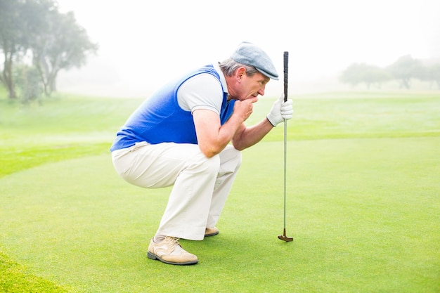 Golfista sério ajoelhado no putting green