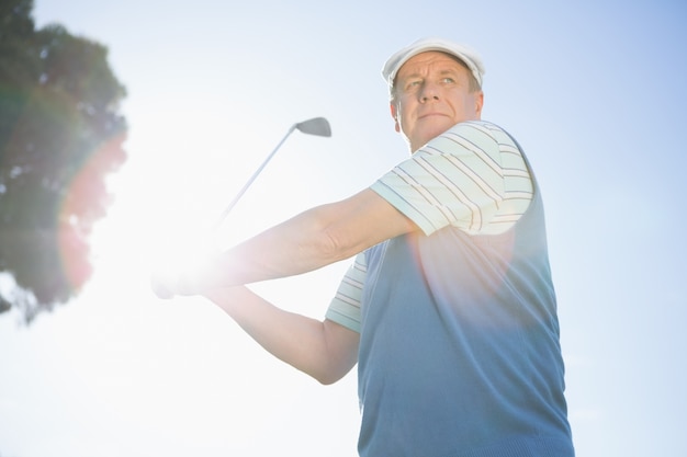 Golfista tomando un tiro y sonriendo