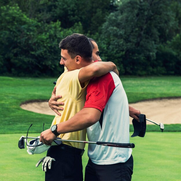 Golfistas abrazándose amistosamente después del juego