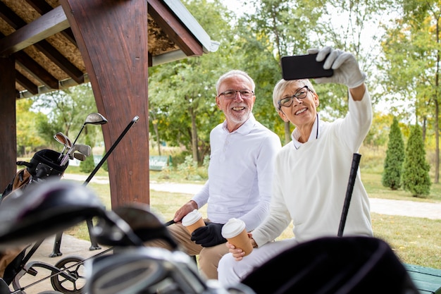 Foto golfistas senior profesionales que se toman selfies antes de jugar al golf para las redes sociales.