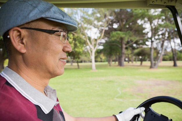 Golfspieler, der Golfbuggy fährt