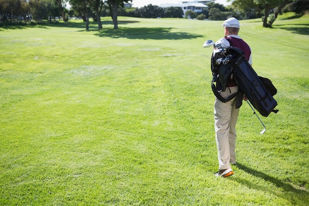 Golfspieler, der seine Tasche und Gehen trägt