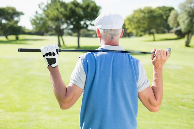 Golfspieler, der seinen Verein hinter seinem Kopf hält