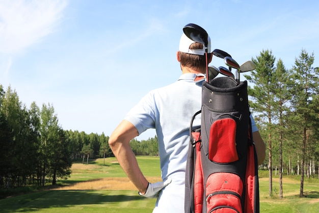 Golfspieler, der während des Sommergolfspiels auf Kurs geht und Tasche trägt.