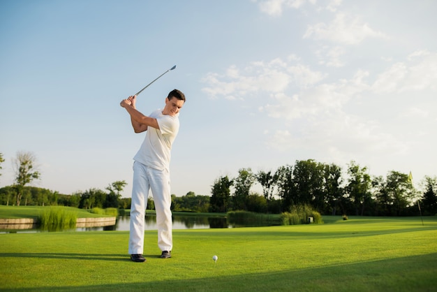 Golfspieler nimmt Schwingen-Schuss auf ordentlichem See des Kurses.