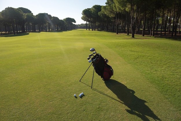 Golftasche auf Kurs mit Schläger und Ball davor bei schönem Sonnenaufgang