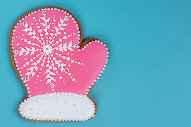 Golosinas de Año Nuevo Navidad manopla pan de jengibre rosa con copos de nieve blancos sobre fondo turquesa