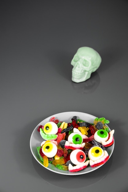 golosinas aterradoras en un plato con una calavera en el costado para celebrar halloween 2022.