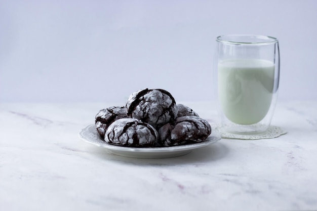 Golosinas en una mesa blanca Galletas de chocolate y un vaso de leche