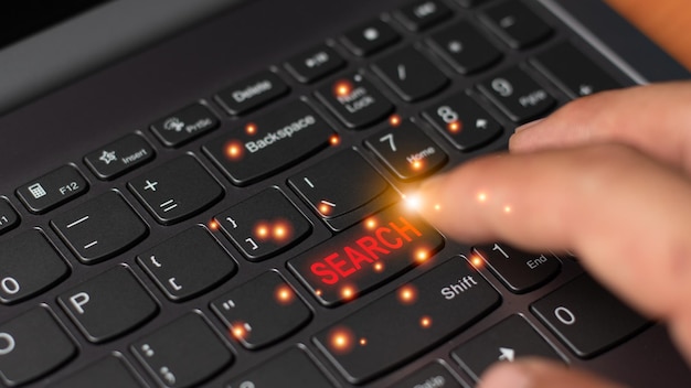 Un golpe de mano en el botón del teclado de búsqueda tecnología de búsqueda concepto en línea luz gráfica de computadora con espacio de copia para texto y diseño