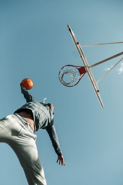 Golpe perfeito. ângulo baixo de um jogador de basquete pulando enquanto tenta jogar a bola na cesta