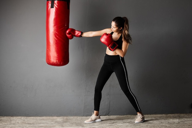 Golpe poderoso Toma completa de una atractiva joven boxeadora entrenando en el gimnasio