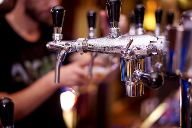 Golpecito de la cerveza con el primer de las gotas en una cerveza de colada borrosa del camarero del fondo en un vidrio.