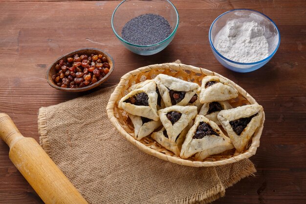 Gomentash con semillas de amapola y ciruelas recién horneadas para la festividad de Purim en una mesa de madera