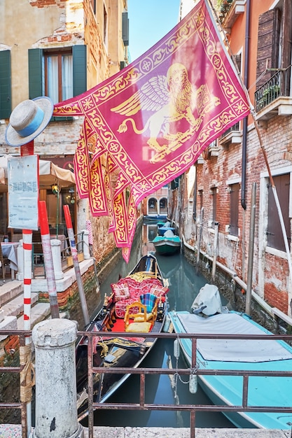 Gondel und die Stadtflagge auf dem Kanal in Venedig, Italien. Sonniger Tag.