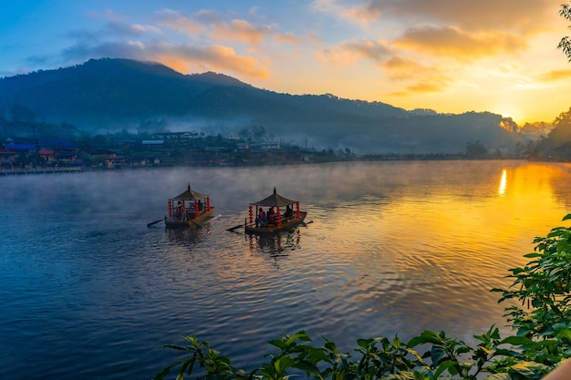 Gondelboot inmitten eines mit Nebel bedeckten Sees bei Sonnenaufgang in der Provinz Mae Hong Son, Thailand